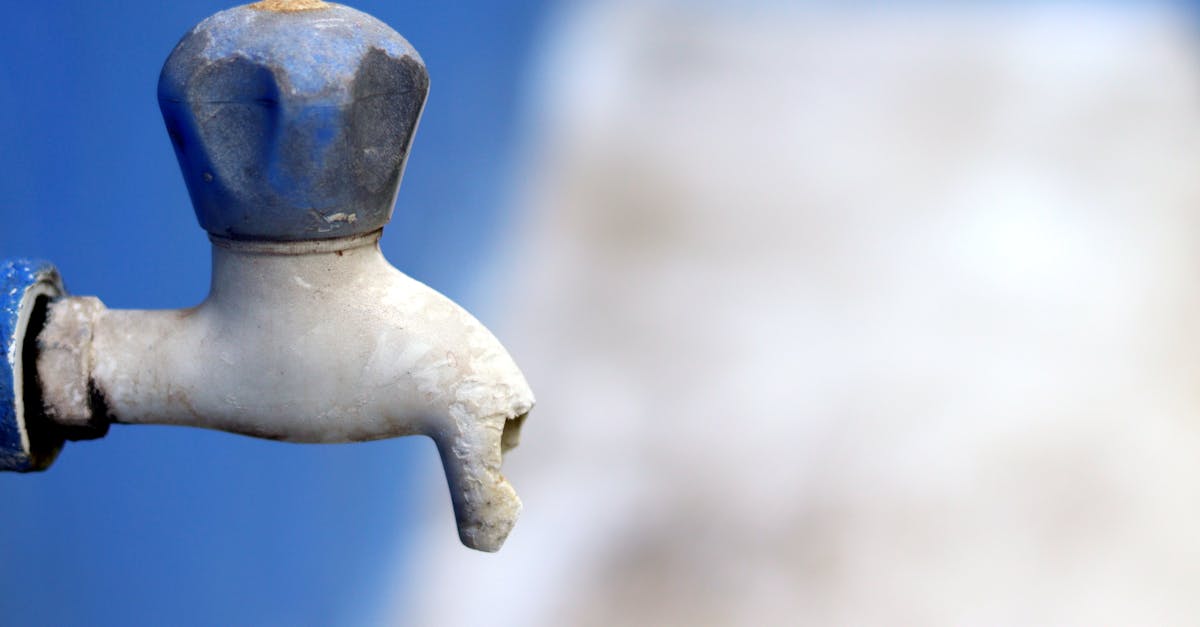 detailed image of a broken faucet against a blurred blue background emphasizing neglect